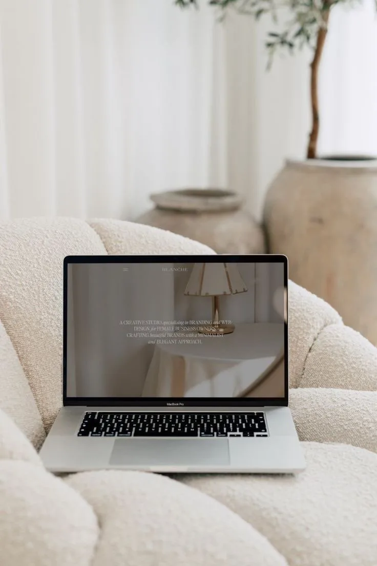 Portátil con una web de Eternal Agency sobre un sofá